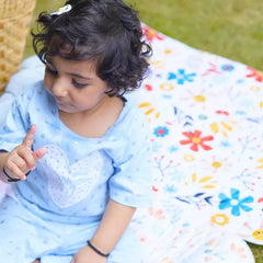 Baby lying on a Happy Matty floral print bed protector mat